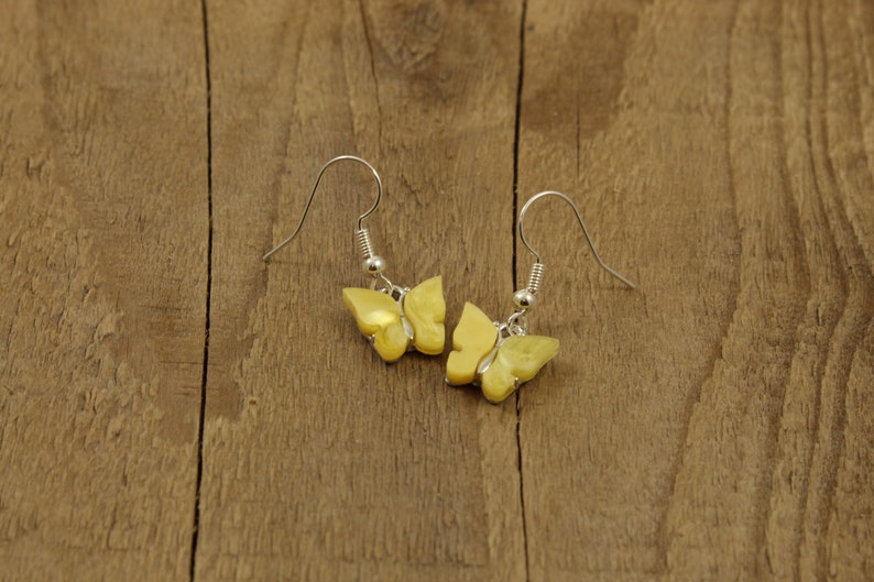 May include: A pair of yellow butterfly earrings with silver hooks.