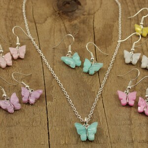 May include: A set of butterfly earrings and a necklace with a matching butterfly pendant. The earrings and pendant are made of iridescent plastic and come in a variety of colors, including pink, blue, white, and yellow.