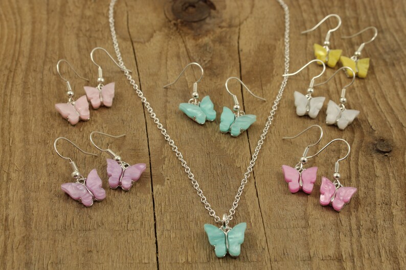 May include: A set of butterfly earrings and a necklace with a matching butterfly pendant. The earrings and pendant are made of iridescent plastic and come in a variety of colors, including pink, blue, white, and yellow.