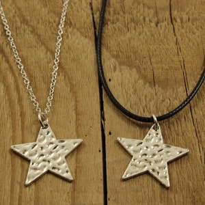 May include: Two silver star necklaces, one on a silver chain and the other on a black cord. Both stars have a hammered texture.