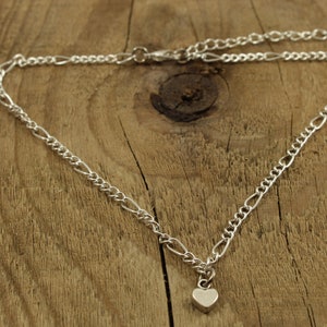 May include: A silver chain necklace with a small heart pendant.