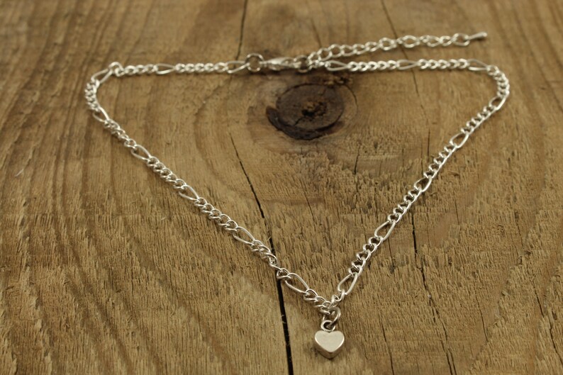 May include: A silver chain necklace with a small heart pendant.