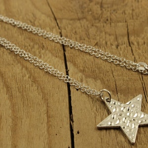May include: A silver chain necklace with a textured star pendant.