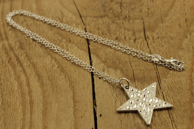 May include: A silver chain necklace with a textured star pendant.