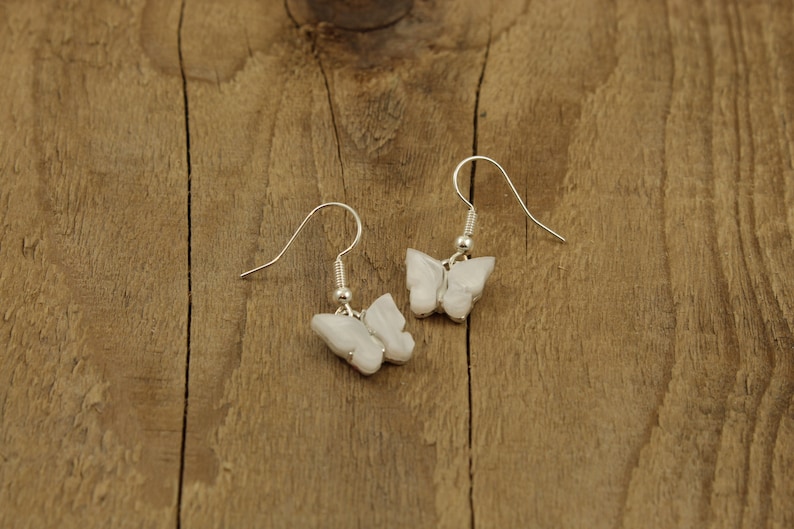 May include: A pair of silver butterfly earrings with white iridescent wings.