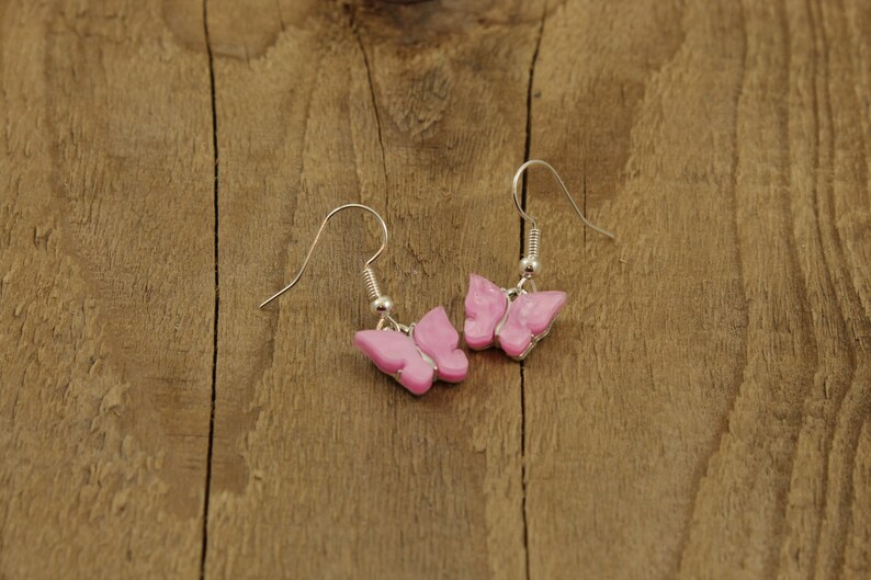 May include: A pair of silver butterfly earrings with pink butterfly charms.