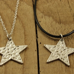 May include: Two silver star necklaces, one on a silver chain and the other on a black cord. Both stars have a hammered texture.