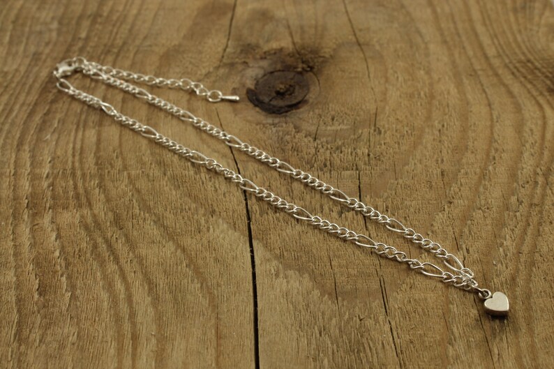 May include: A silver chain necklace with a small heart pendant.