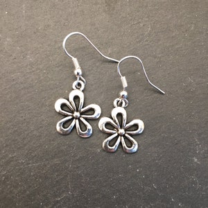 Pu&ograve; includere: Un paio di orecchini pendenti a forma di fiore in argento con un design semplice.