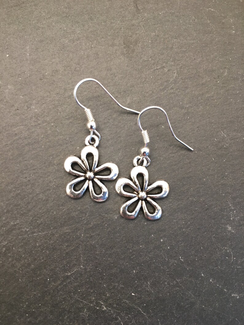 Pu&ograve; includere: Un paio di orecchini pendenti a forma di fiore in argento con un design semplice.