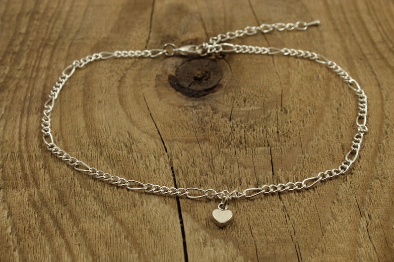 May include: A silver chain anklet with a small heart charm.