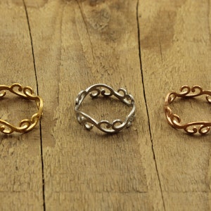 May include: Three delicate rings with a swirling, ornate design. The rings are made of gold, silver, and rose gold.