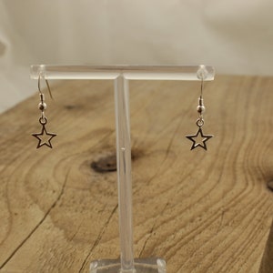 May include: A pair of silver star-shaped dangle earrings with a small bead at the top of each earring.