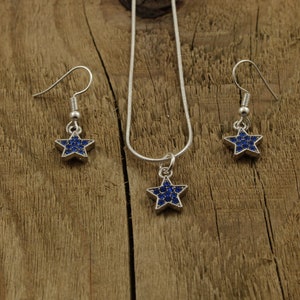 May include: A silver necklace and earrings set with a blue star-shaped pendant and matching earrings. The stars are covered in small blue rhinestones.