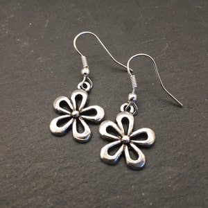 Pu&ograve; includere: Un paio di orecchini pendenti a forma di fiore in argento con un design semplice. Gli orecchini hanno una chiusura a gancio.