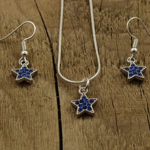 May include: A silver necklace and earrings set with a blue star pendant and matching earrings. The star is covered in small blue rhinestones.