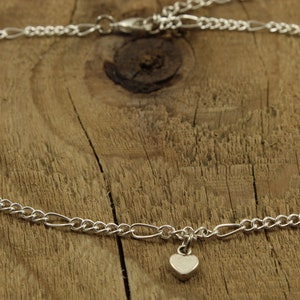 May include: A silver chain anklet with a small heart charm.