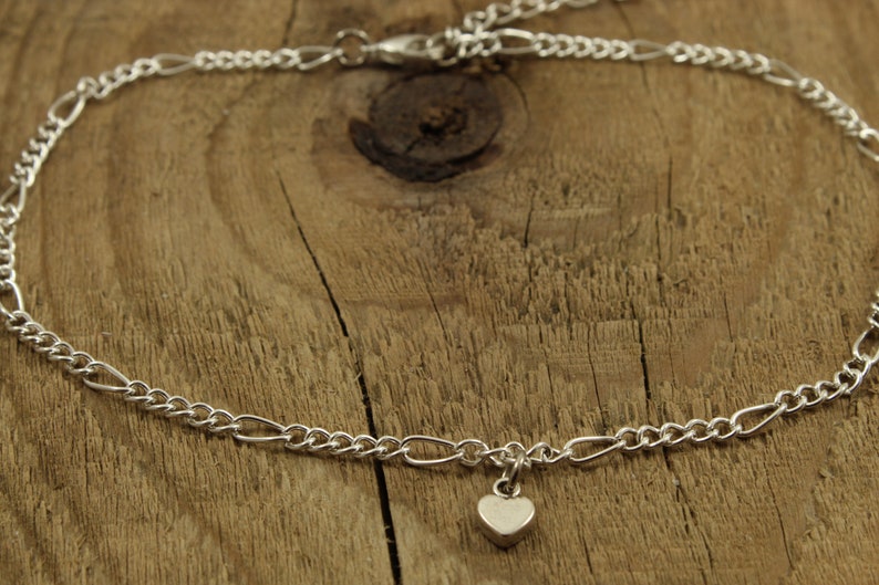 May include: A silver chain anklet with a small heart charm.