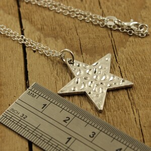 May include: A silver chain necklace with a hammered silver star pendant. The star is approximately 3 inches wide.
