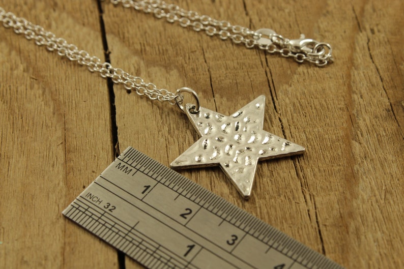 May include: A silver chain necklace with a hammered silver star pendant. The star is approximately 3 inches wide.
