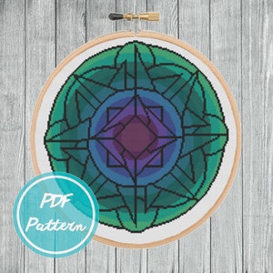 May include: A cross-stitch pattern of a colorful mandala with a green, blue, and purple color scheme. The mandala is in a round embroidery hoop.