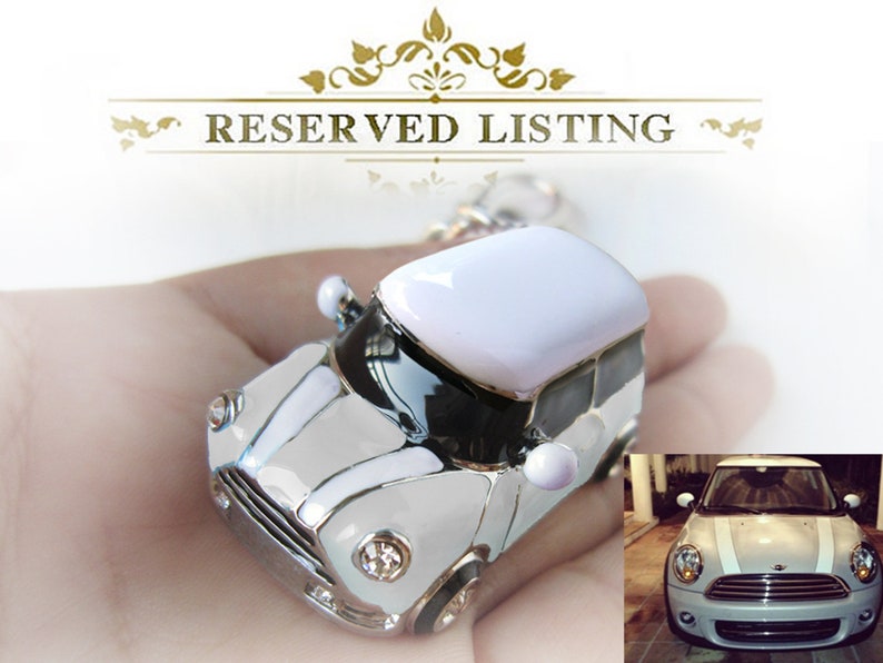 May include: A miniature white and silver car keyring with a white roof and black detailing. The keyring features a detailed design and a small image of a car in the bottom right. The text "RESERVED LISTING" is at the top.