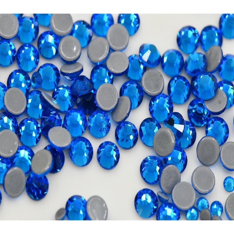 May include: A scattering of blue rhinestones with silver backs. The rhinestones are round and have a faceted surface.