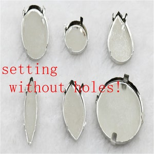 Könnte beinhalten: Sechs silberne Metallfassungen für Strasssteine oder andere Edelsteine. Die Fassungen haben verschiedene Formen, darunter oval, rund und tropfenförmig. Die Fassungen sind zum Kleben oder Löten auf eine Oberfläche ausgelegt. Der Text "setting without holes!" ist im Bild sichtbar.