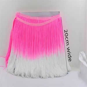 May include: A bright pink and white fringe trim, 20 cm wide, with a band at the top. The fringe fades from pink to white. This decorative trim is suitable for various craft projects.