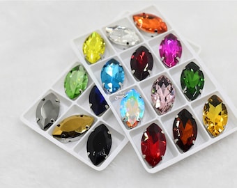 May include: Assortment of 12 marquise-shaped rhinestones in a clear plastic storage case. The rhinestones are in various colors, including red, blue, green, yellow, orange, pink, and black.
