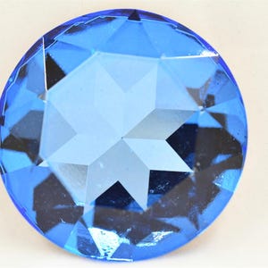 May include: A large, faceted, blue crystal gem with a star-shaped pattern in the centre.