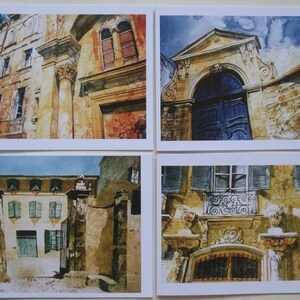 May include: Four watercolor paintings of old buildings in a European city. The paintings are in a muted color palette of browns, yellows, and blues. The buildings have arched doorways, windows, and intricate details.
