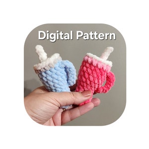 May include: Two crocheted mugs, one blue and one pink, with white tops and a white crocheted straw. The mugs are held in a hand. Digital Pattern.