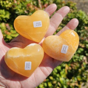 May include: Three heart-shaped orange calcite crystals, each with a label that reads "Made in Mexico".