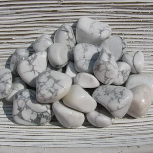 May include: A pile of white and gray tumbled stones. The stones are smooth and have a natural, polished look.