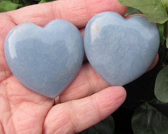 May include: Two light blue heart-shaped polished stones. The stones are smooth and have a slightly cloudy appearance.