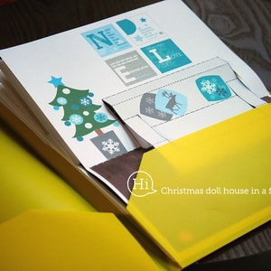 Puede incluir: Una carpeta amarilla con un inserto de papel blanco. El inserto de papel tiene un &aacute;rbol de Navidad, un reno y copos de nieve. La carpeta tiene el texto "Hi Christmas doll house in a folder" impreso en ella.