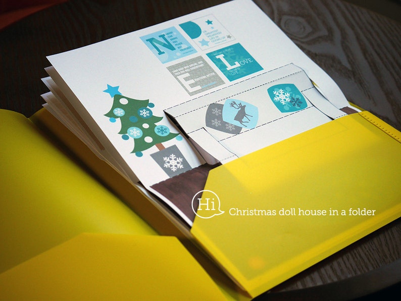 Puede incluir: Una carpeta amarilla con un inserto de papel blanco. El inserto de papel tiene un &aacute;rbol de Navidad, un reno y copos de nieve. La carpeta tiene el texto "Hi Christmas doll house in a folder" impreso en ella.