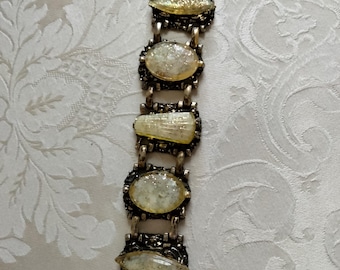 May include: A silver bracelet with a chain link design and five oval-shaped, iridescent glass stones. The stones are set in silver bezels and have a sparkly, glittery finish.