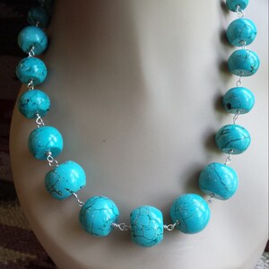 May include: A turquoise blue necklace with large round beads connected by silver wire.