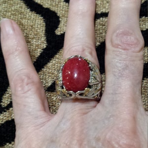 May include: A silver ring with a red gemstone set in a floral design.