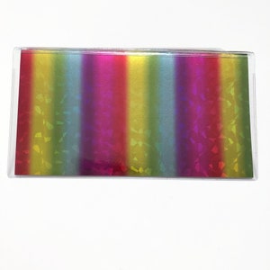 May include: A clear plastic wallet with a rainbow iridescent pattern. The wallet has a vertical orientation and is made of a clear plastic material.