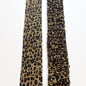 May include: Two pieces of fabric with a leopard print pattern. One piece is flat and the other is gathered.