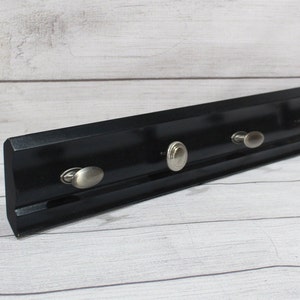May include: Black wooden wall mounted key holder with four silver metal hooks.