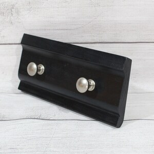 May include: Black wooden key holder with two silver knob hooks.
