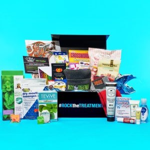 May include: A black box filled with various items, including a crossword puzzle book, a bag of nuts, a tube of hand cream, a box of peppermint tea, and a t-shirt with the text "#ROCKtheTREATMENT".