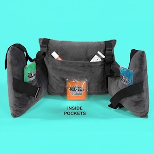May include: A dark gray, plush body support system with adjustable straps and multiple pockets. The center section has a large pocket, and the side supports have smaller pockets. The image shows the text "Rock Treatment" on the products inside the pockets. The text "INSIDE POCKETS" is also visible.