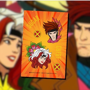 May include: A bright orange and yellow card with a comic book style illustration of two characters. The top character is a man with red hair and a red and white flame design. The bottom character is a woman with red and white hair and a flower design. The text "Sugar Cereb" is on the card.