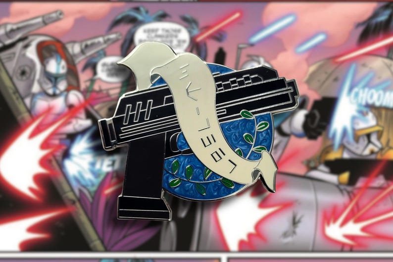 Puede incluir: Un pin de esmalte negro y plateado con forma de pistola con una pancarta blanca con texto. El pin est&aacute; colocado sobre un fondo azul con un dise&ntilde;o de corona de laurel verde. El fondo es un panel de c&oacute;mic.