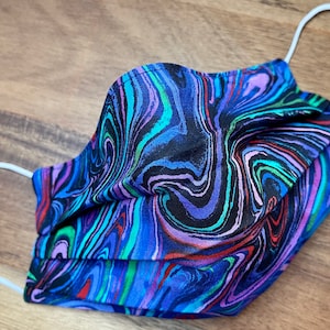 May include: A blue, black, green, and purple face mask with a swirled pattern. The mask has white elastic ear loops.